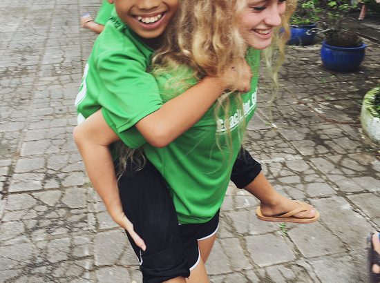 ACE Student-Athlete Giving Camper a Piggyback Ride