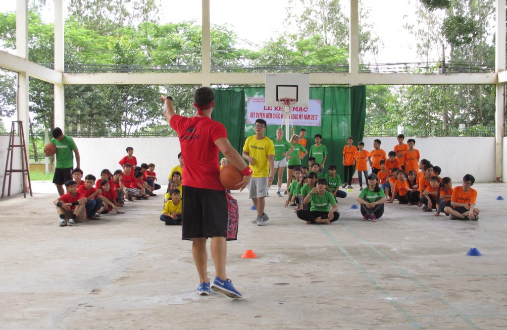 student-athlete teaaching basketball to kids