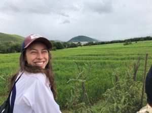 student smiling with field and mountains in background