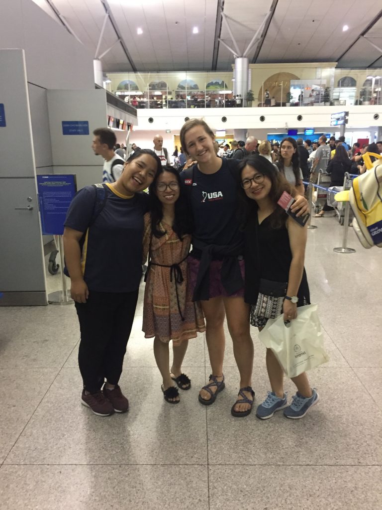one American and three Vietnamese college students with arms around each other in the airport