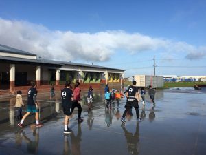 Coaches and children playing outside on wet ground