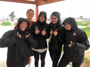 five students in rainjackets giving thumbs up sign