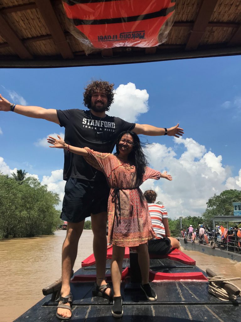 Two people stand on boat in middle of river