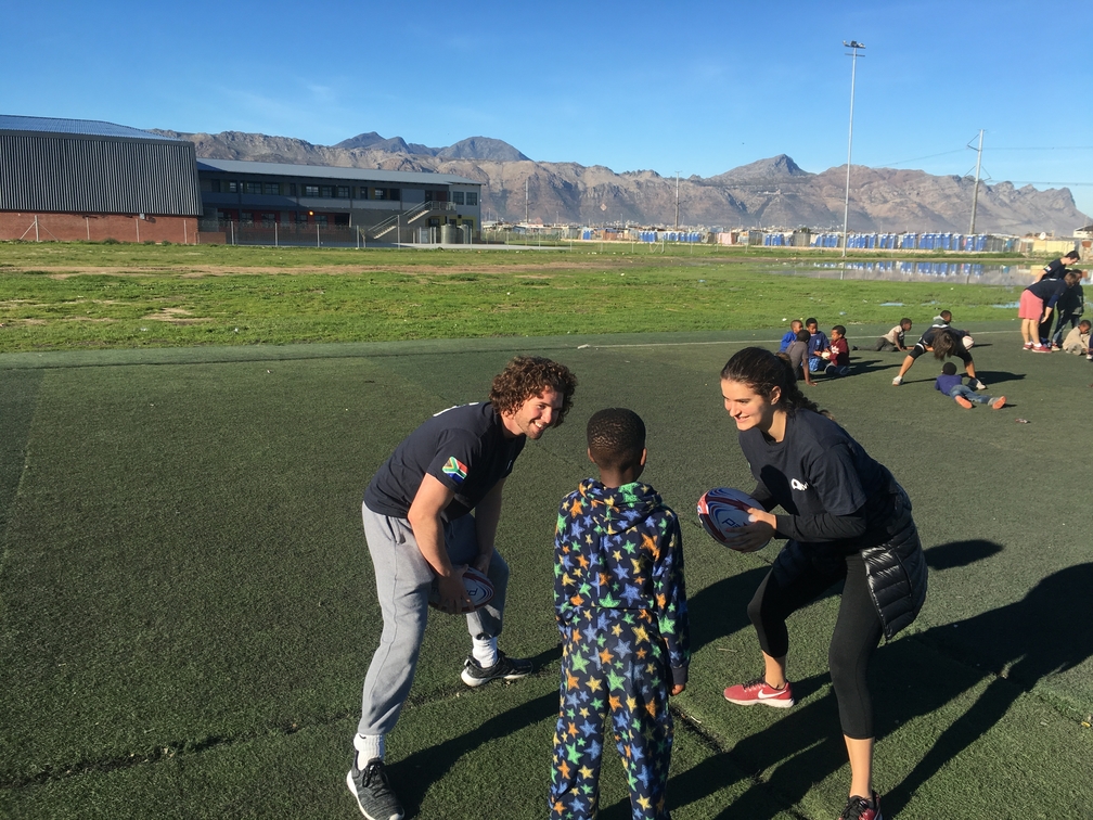 three people playing rugby on a field