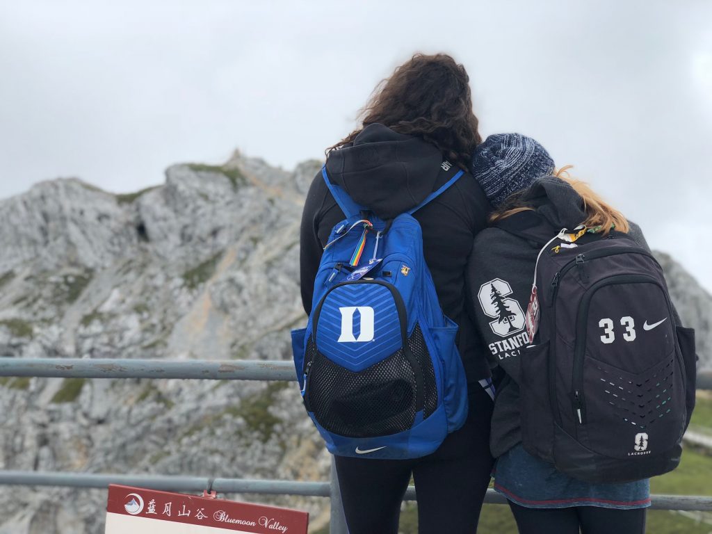 two students standing side by side with back to camera and arms around each other