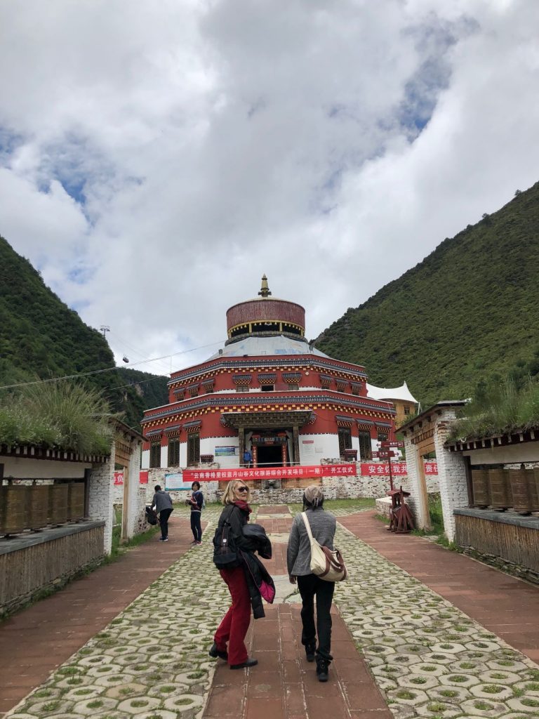 two people walking toward a building in the mountains