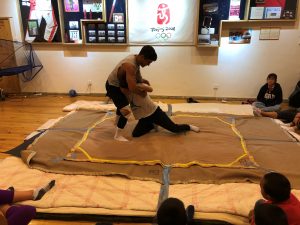 student athlete wrestling younger student on a mat