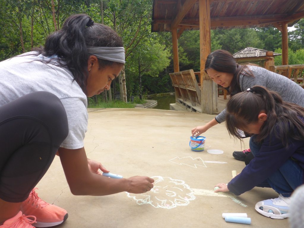 three people drawing with chalk