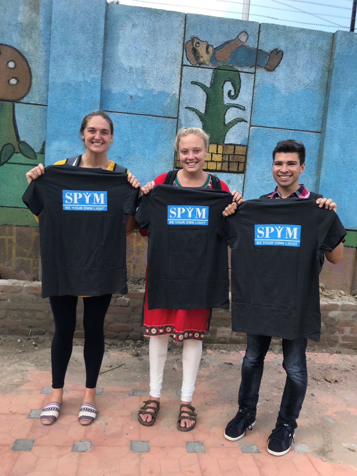 three students holding a t-shirt