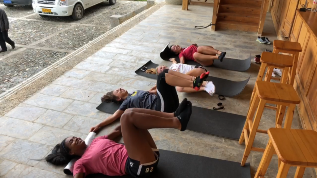 four students working out on mats on the floor