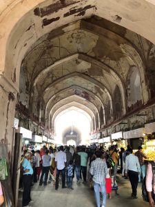 crowd of people walking through an old stone arched building hallway