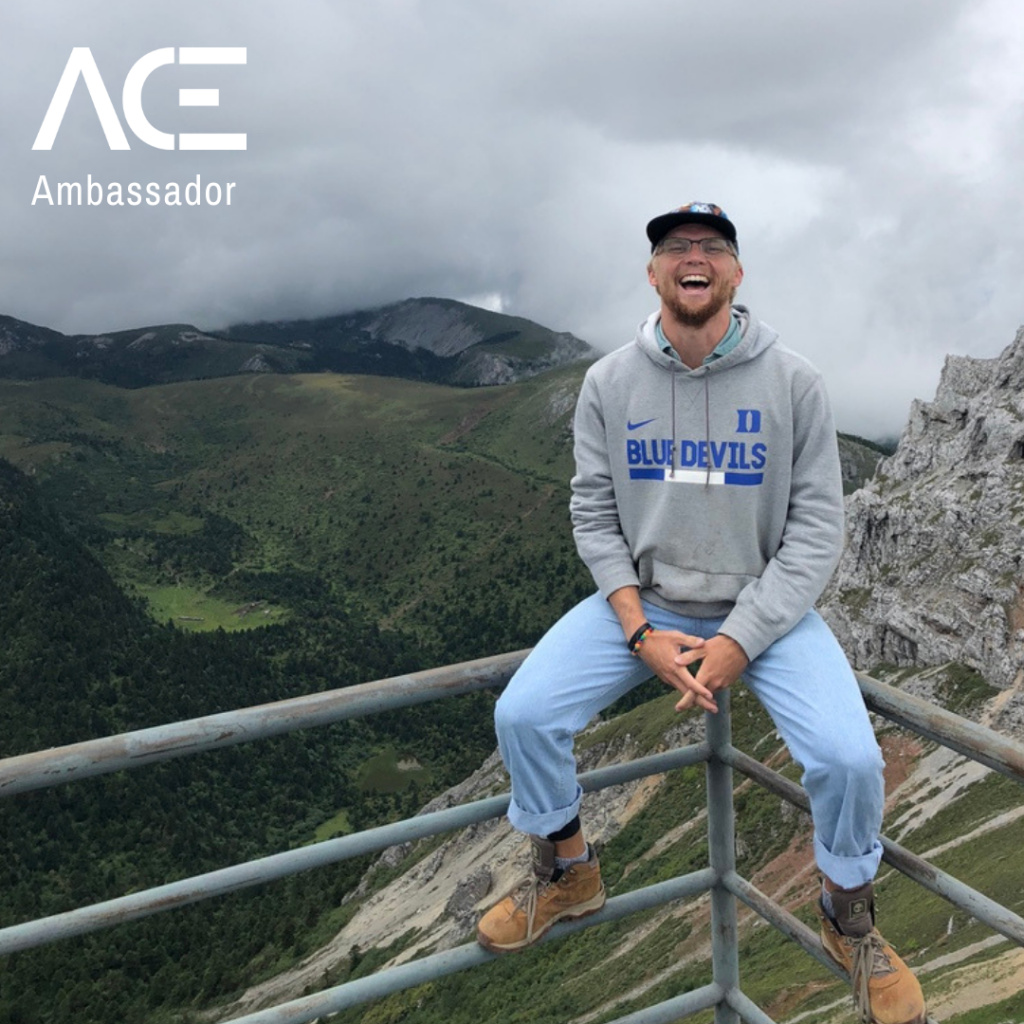 male student-athlete sitting on ledge overlooking mountain