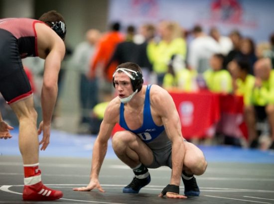 male wrestler crouching down on mat preparing to fight