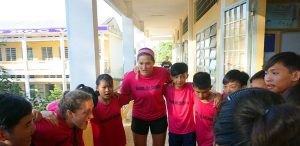 student-athlete and schoolchildren talking in a sports huddle