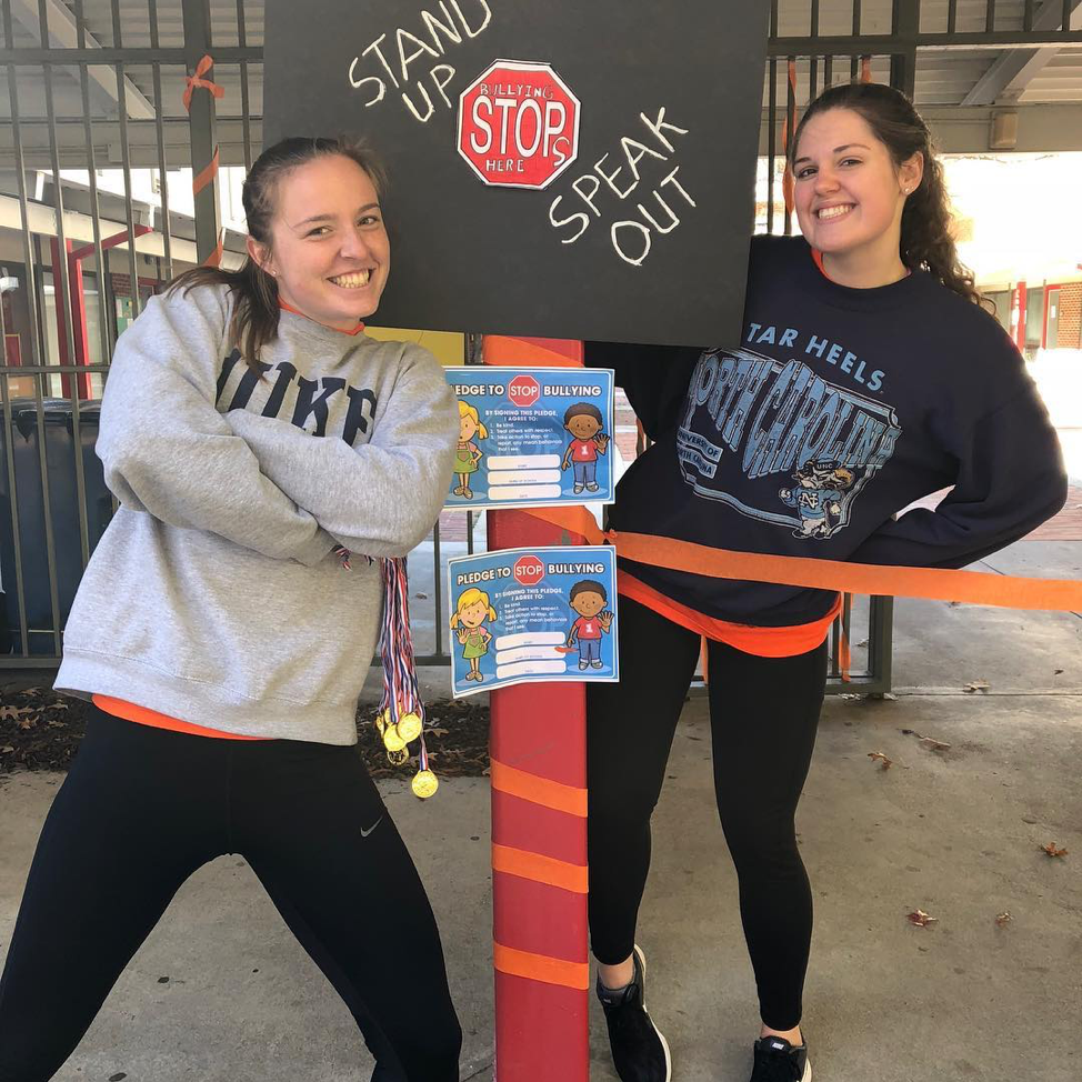 two women standing in front of poster about bullying