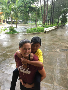 student-athlete giving kid piggyback ride outside in the rain