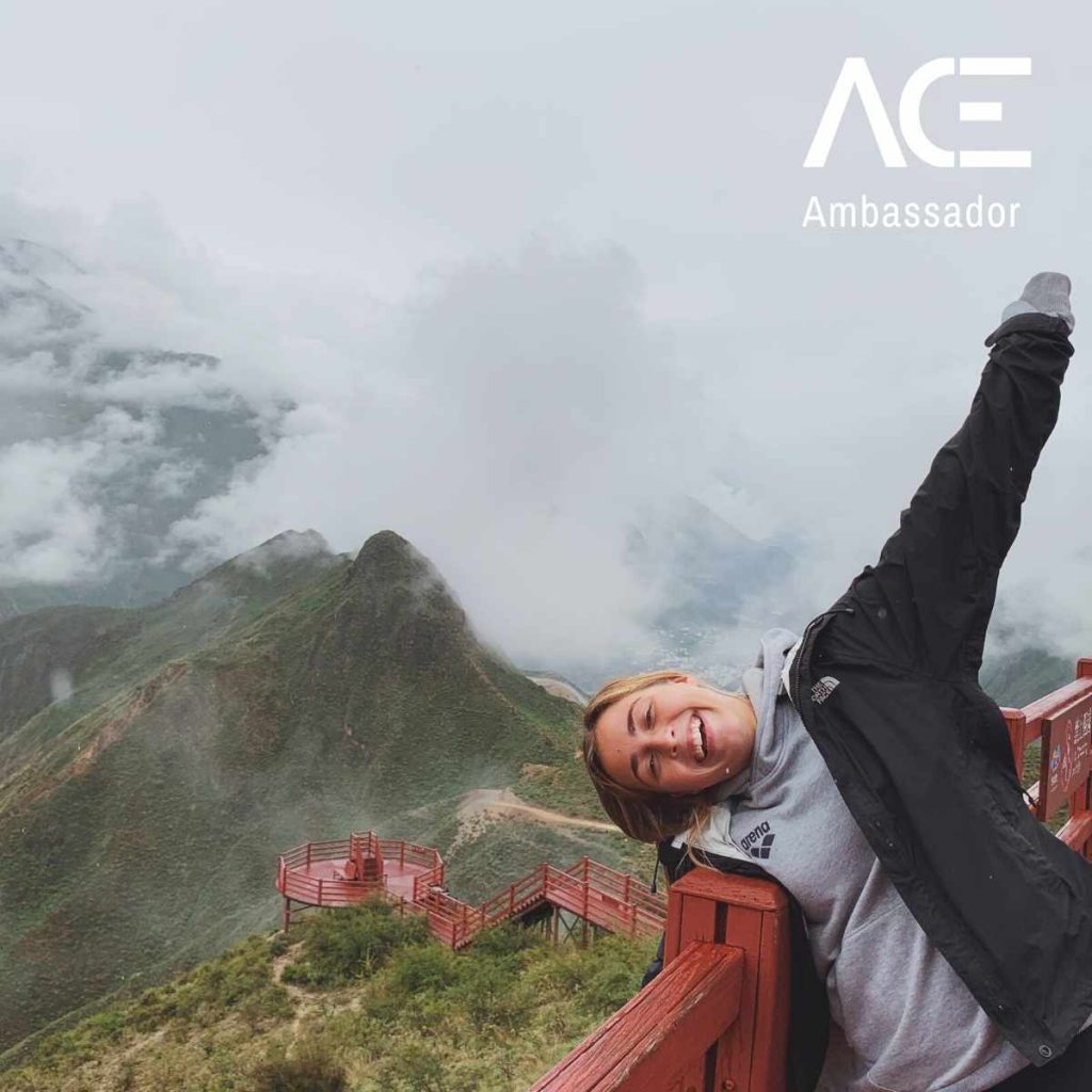 woman posing with arms raised next to a mountain