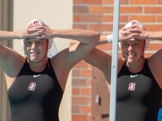 two female twins wearing swimsuits and swimcaps at a meet outside
