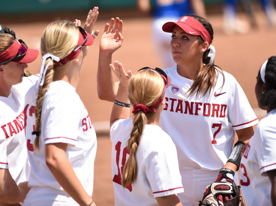 women huddling in softball uniforms on field outside