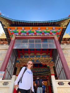 female standing in front of colorful monastery door