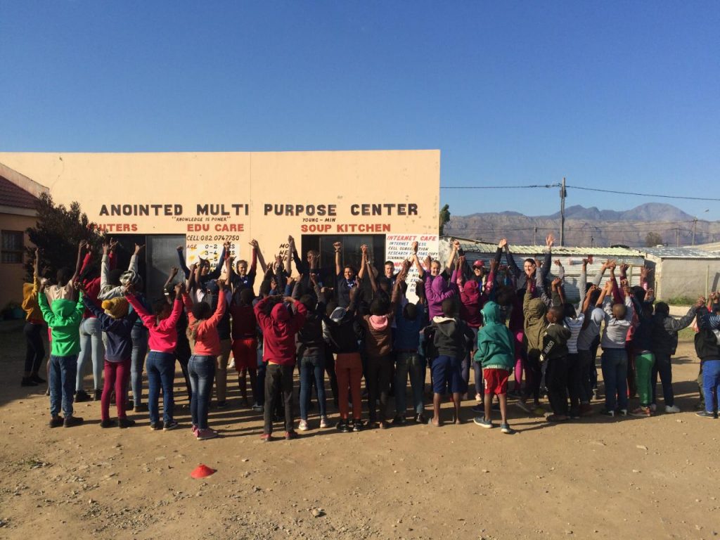 group of kids outside school building raising hands