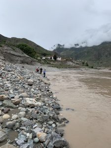 people in the distance skipping rocks along a river