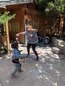 young adult hula hooping while child watches