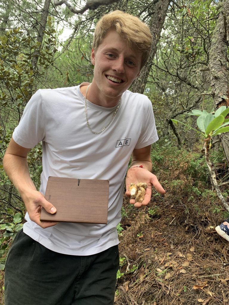 student holding mushrooms outside