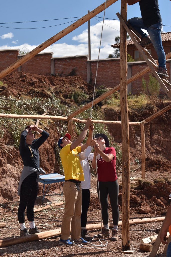 group of young people building wooden structure outside