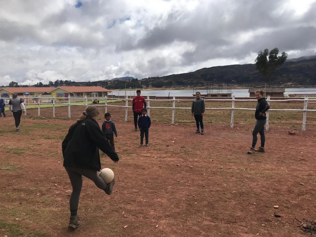 student playing soccer outside with kids