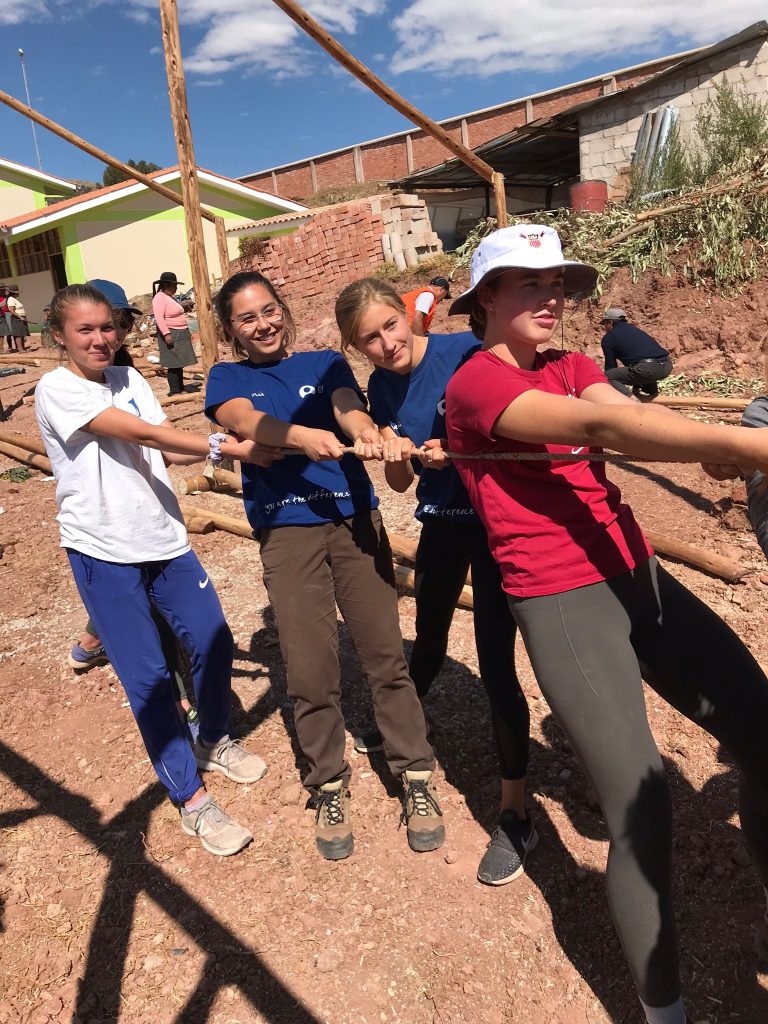 group of student-athletes constructing greenhouse with wood