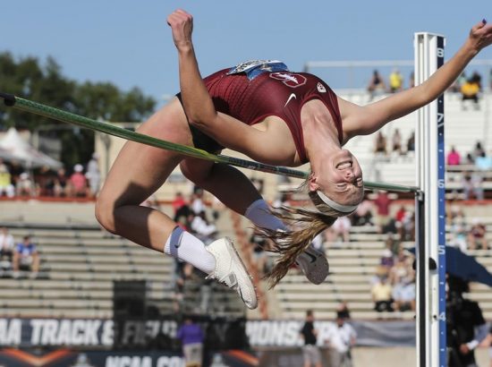 young woman jumping over high hurdle