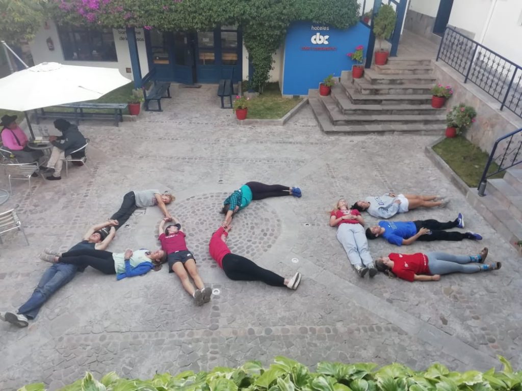 students lying down on the ground to form the word "ACE"