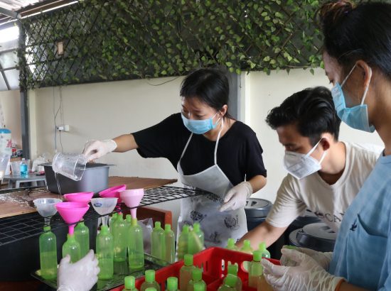 people wearing masks filling up soap bottles using funnel