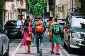group of people walking along the street in backpacks and bright clothing