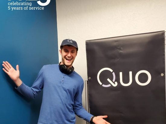 man posing in front of sign that says "quo"