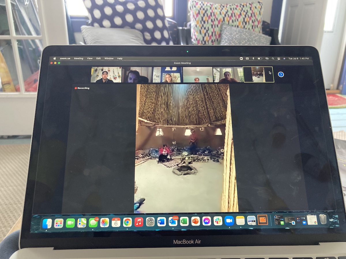 laptop screenshot of people huddled in circle in hut