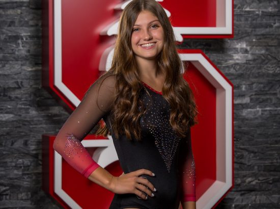 headshot of woman in leotard in front of stanford logo