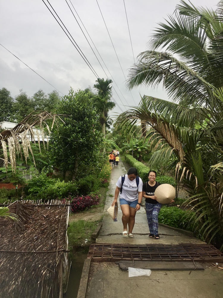 women walking through tree alleyway