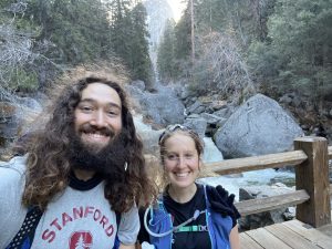 man and woman smiling in front of waterfall hike