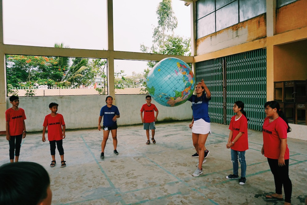 woman holding blow up globe in circle with children